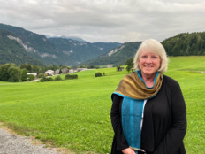 Heidi Tilghman, director of CAS AST, standing in front of a grassy field and mountains