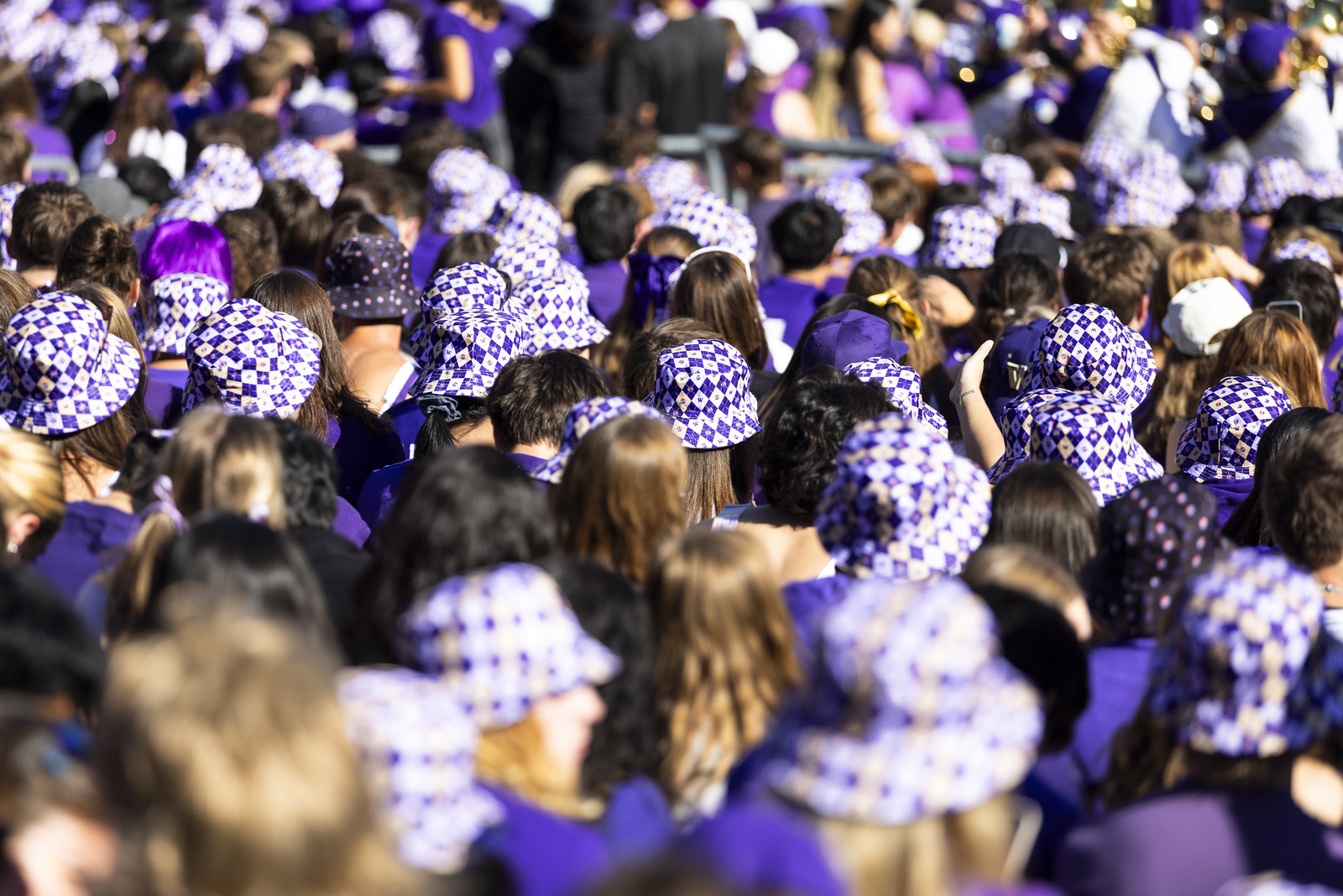People walking in a crowd while wearing UW branded bucket hats