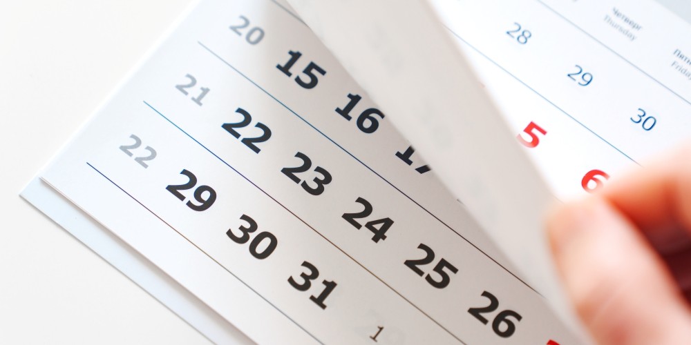A person flipping through a calendar of dates.