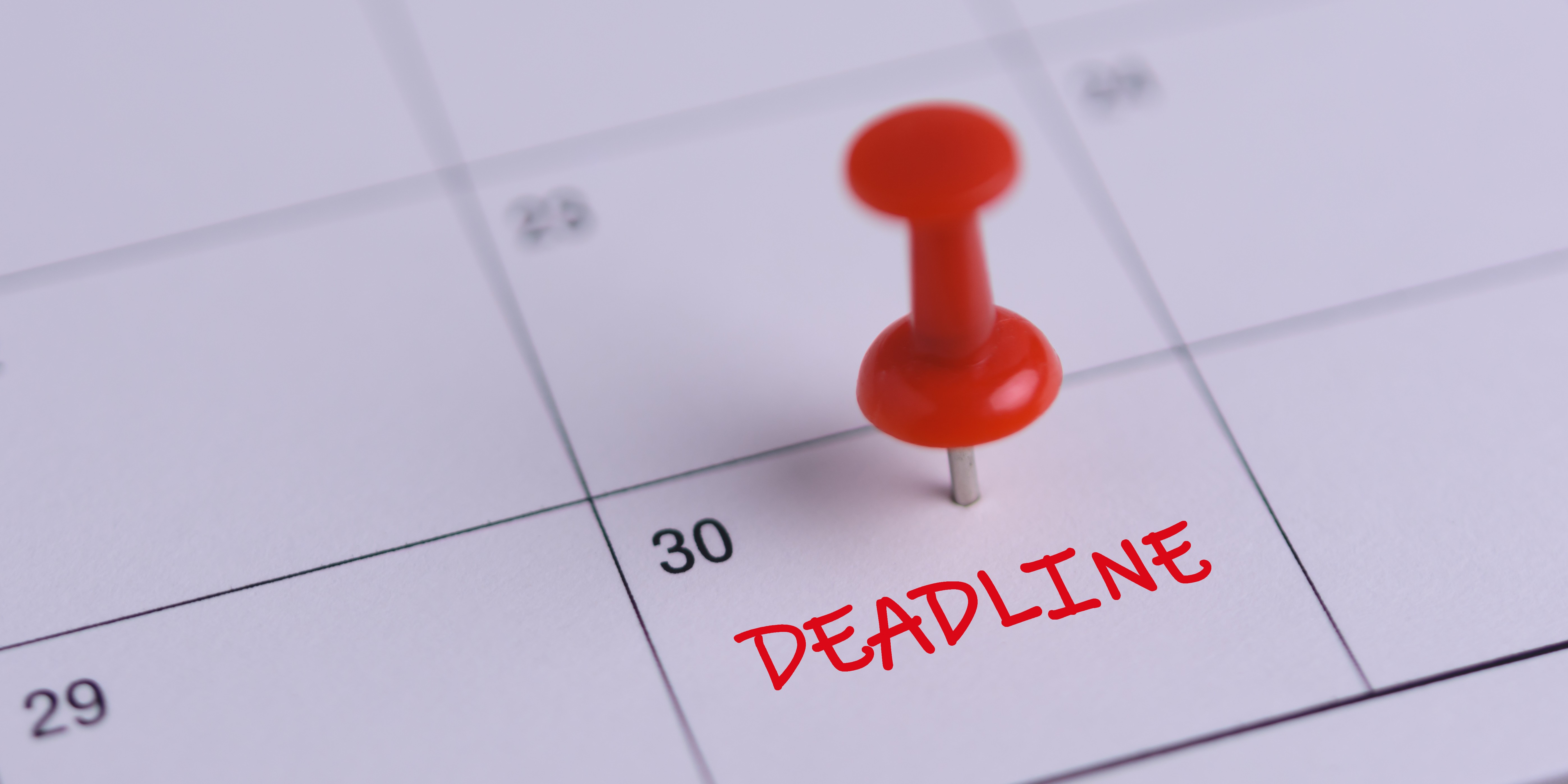 A pushpin in a calendar marking the 30th as the deadline date